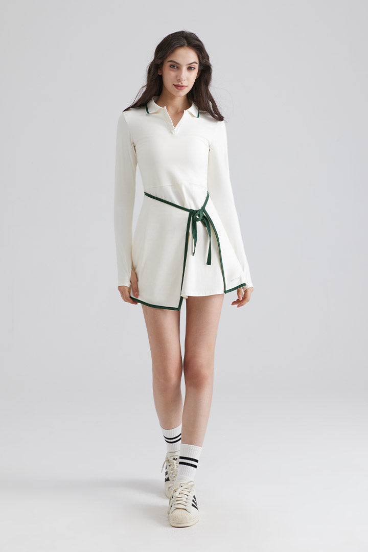 Woman wearing a white dress with green trim on a plain background