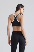 Woman wearing a black sports Yoga bra and leggings with white accents