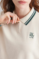 Close-up of a women wearing a beige polo sweater with collar